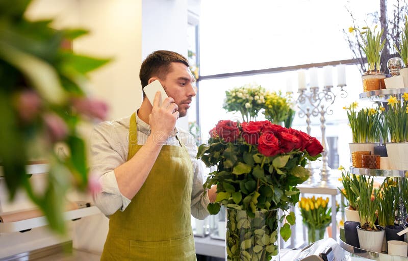 Man med smartphonen och röda rosor på blomsterhandeln arkivbilder Man med smartphonen och röda rosor på blomsterhandeln arkivbilder