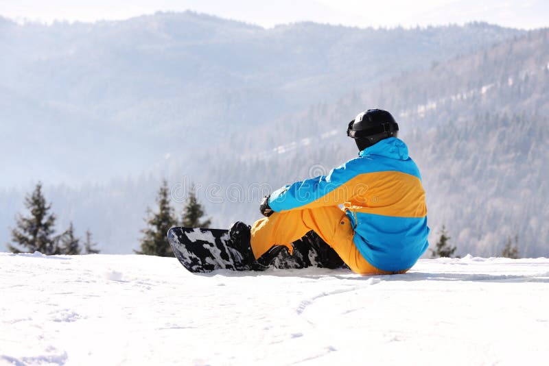 Man med snowboarden som vilar i berg Vinter arkivfoton Man med snowboarden som vilar i berg Vinter arkivfoton