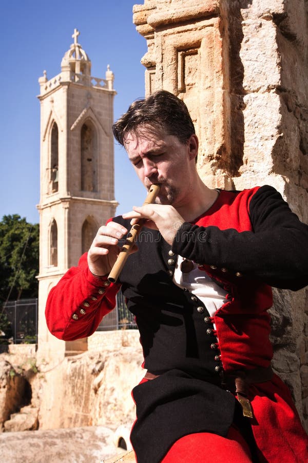 Man in a medieval suit plays a flute