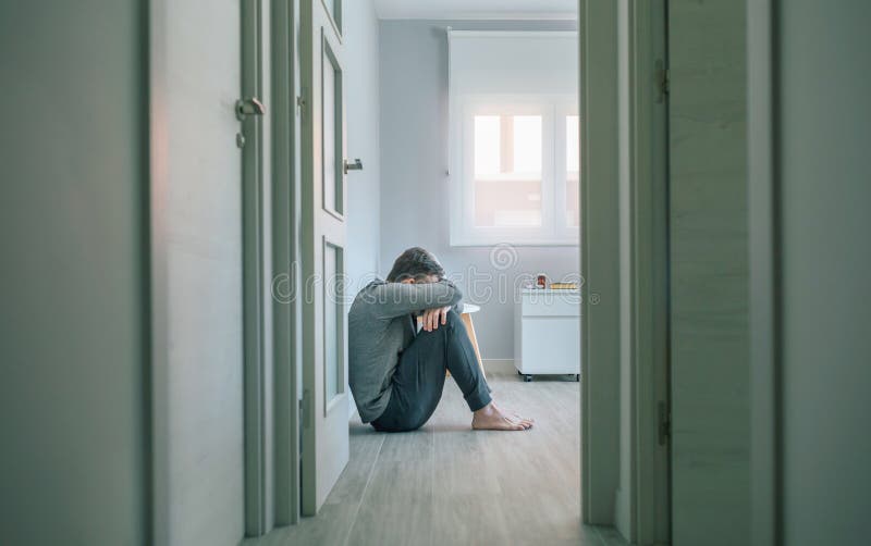 Man with mental disorder crying sitting on room floor royalty free stock photo
