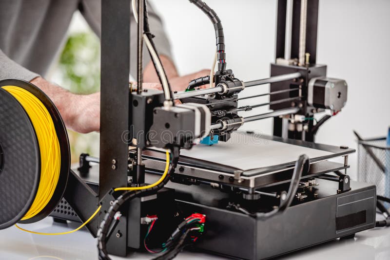 Closeup view of modern 3D printer technology equipment and man hands working with it. Closeup view of modern 3D printer technology equipment and man hands working with it