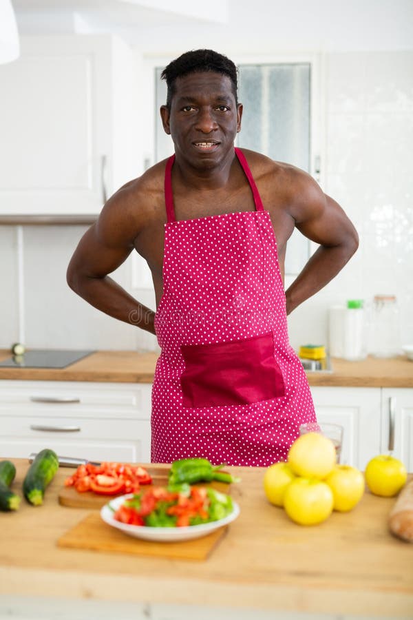 Man with a Naked Torso in an Apron Prepares a Vegetable Salad in the
