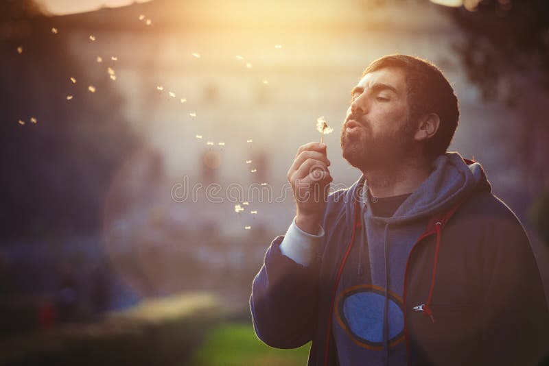 Man in nature. Harmony and romance. Dandelion blowing