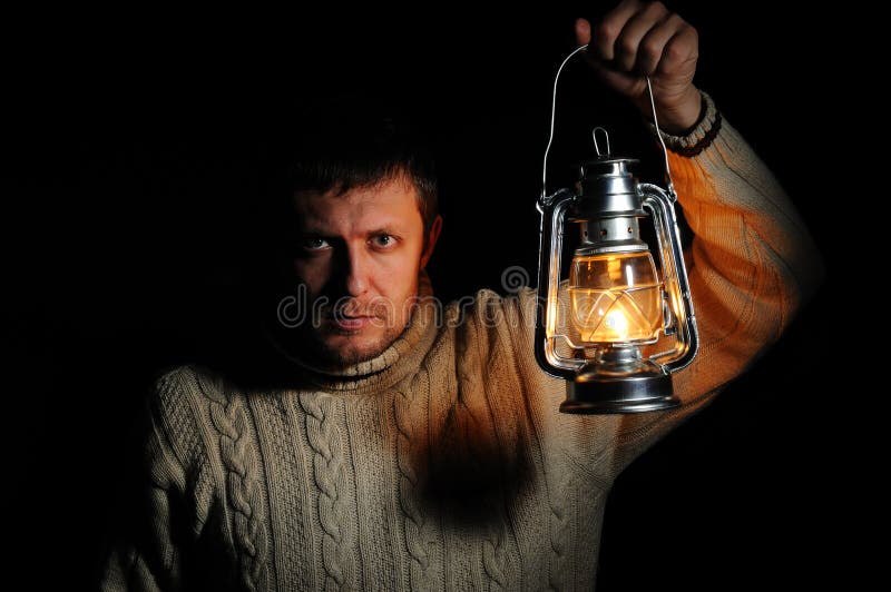 Man in the night with a burning kerosene lamp stock image
