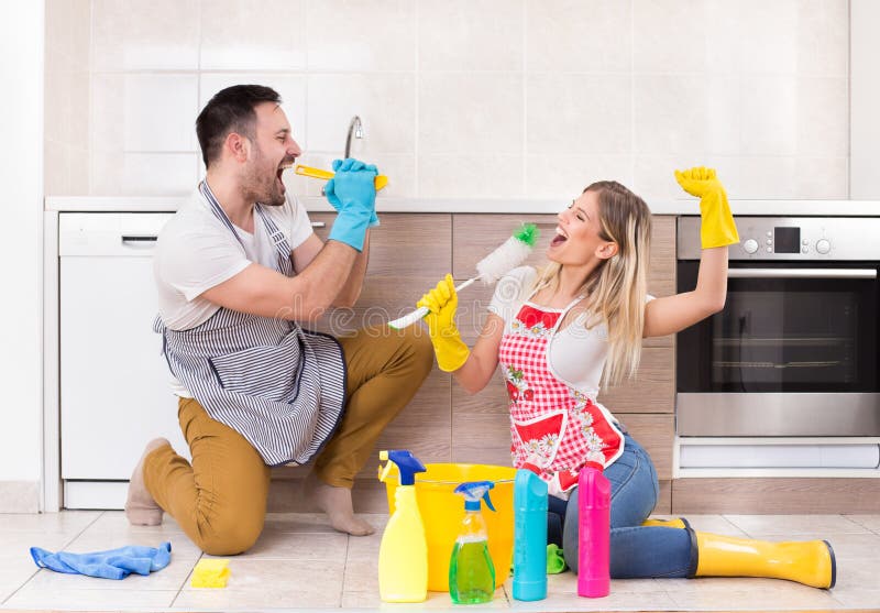 Young couple singing and having fun on kitchen floor after finishing chores. Young couple singing and having fun on kitchen floor after finishing chores