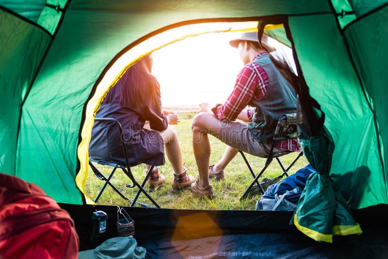 Man och kvinnliga campare som talar varje andra framme av det campa t? ltet Folk och livsstilbegrepp Picknick- och loppbegrepp royaltyfri fotografi