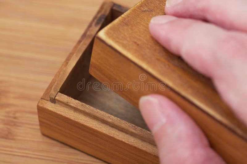 A man opening a small old empty wooden box with his hand royalty free stock photo