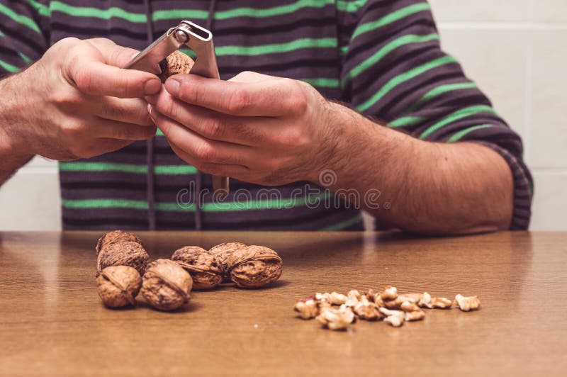 Man opening some walnuts on a table. Hands detail