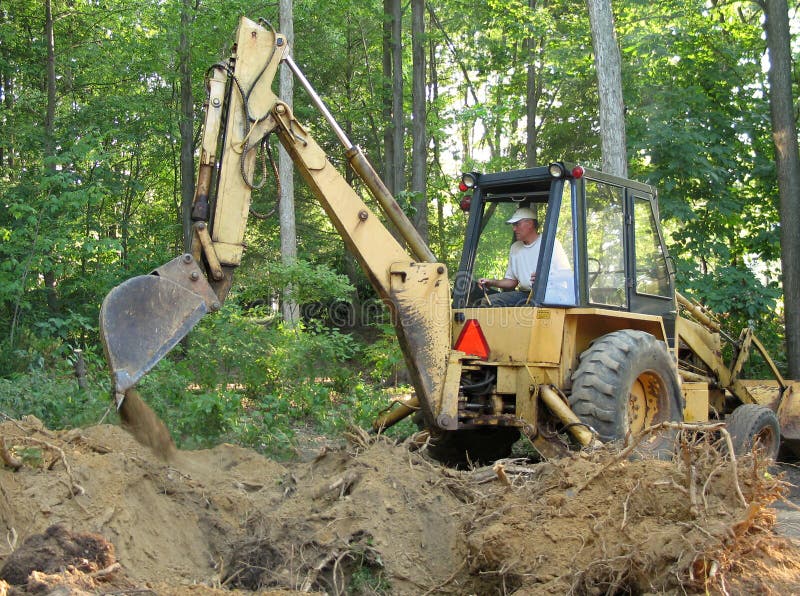 Man removing tree roots with a backhoe. Claw machine stock images, royalty-free photos and pictures