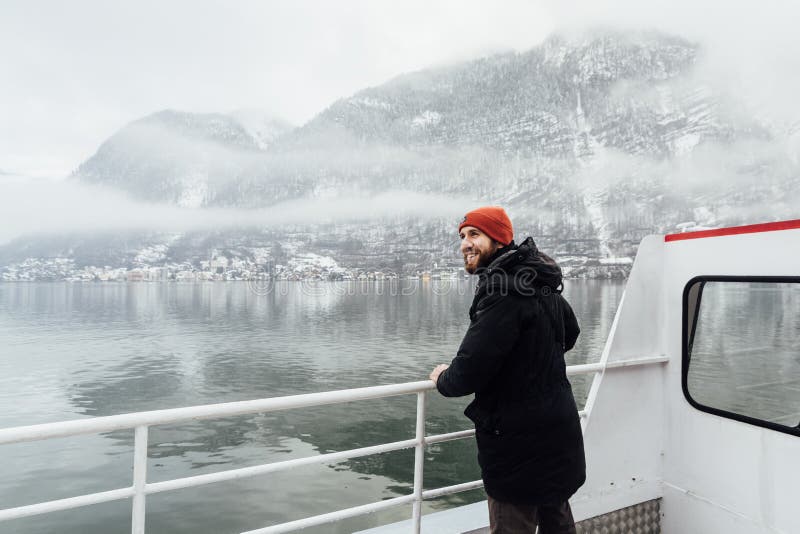 Man in orange hat standing on a ferry deck on the way to Hallstatt, Austria