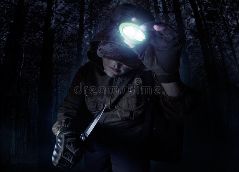 Man in outfit jacket, gloves and knife turning on head flashlight