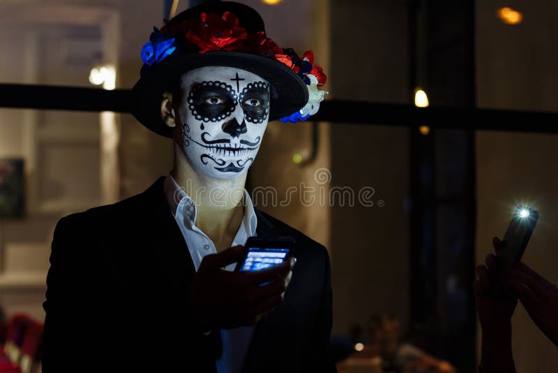 A man with a painted face of a skeleton, a dead zombie, in the city during the day. day of all souls, day of the dead, halloween, stock photo A man with a painted face of a skeleton, a dead zombie, in the city during the day. day of all souls, day of the dead, halloween, stock photo