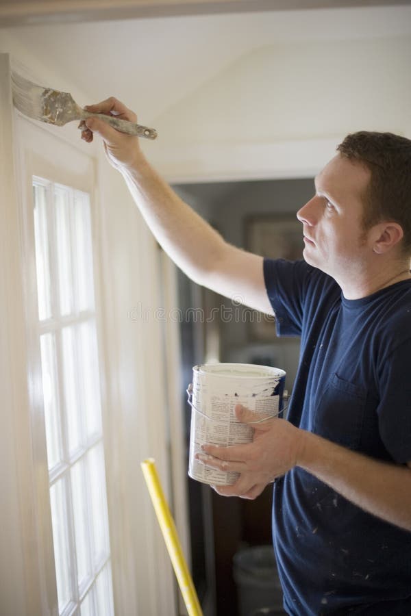 Giovane pittura di rivestimento della porta all'interno di una casa.