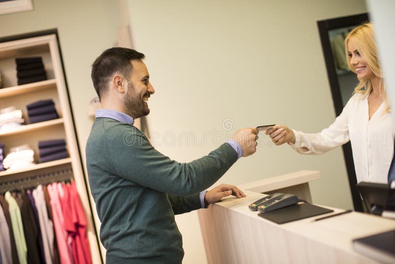 Man paying female sales assistant with credit card in clothes shop stock images Man paying female sales assistant with credit card in clothes shop stock images