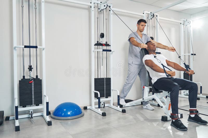 Man Performing Seated Straightarm Pulldown Aided by Kinesiologist