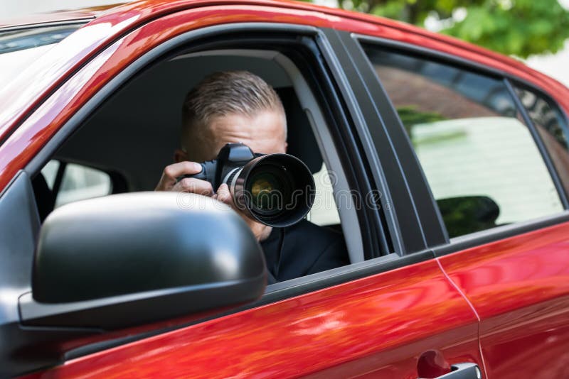 Man photographing with slr camera from car