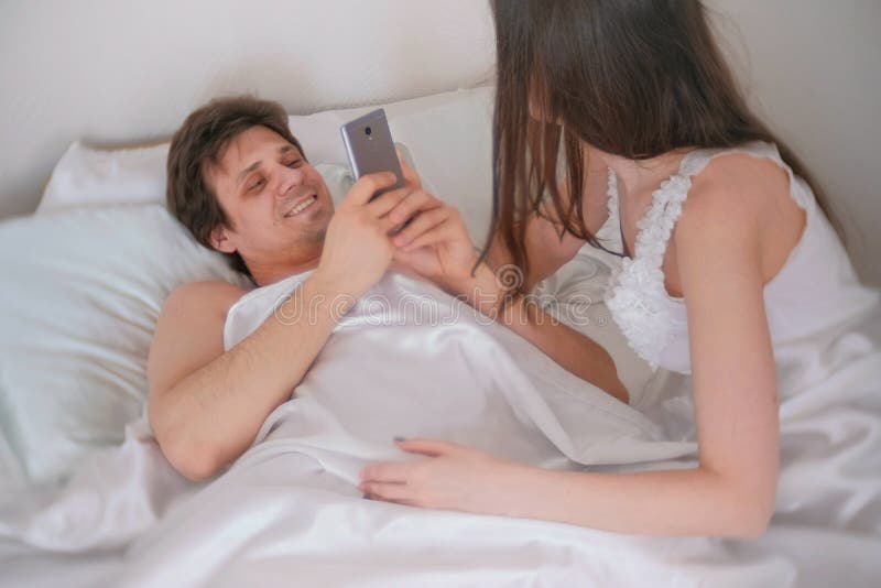 Man Photographs a Woman on Mobile Phone. Couple Man and Woman Lying in