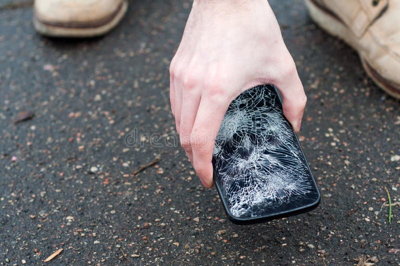 Man picking up broken smartphone from the ground. Damaged mobile phone with cracked touch screen royalty free stock photos Man picking up broken smartphone from the ground. Damaged mobile phone with cracked touch screen royalty free stock photos