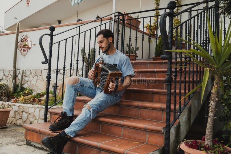 Man Playing Accordion On The Stair Steps Of His House royalty free stock photo