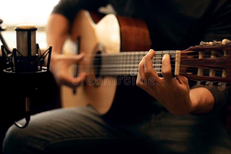 Man Playing a Spanish Guitar and Recording with a Microphone Stock