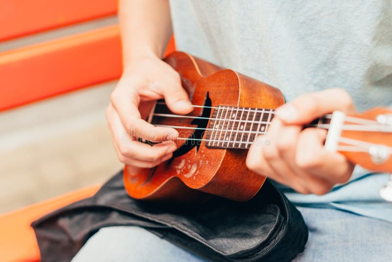 Man Strumming An Ukulele/guitar In The Woods Next To An Open Bonfire