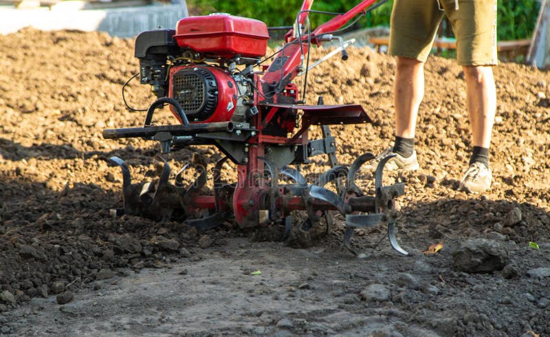 Man plowing land with walk-behind tractor. Selective focus. stock photos