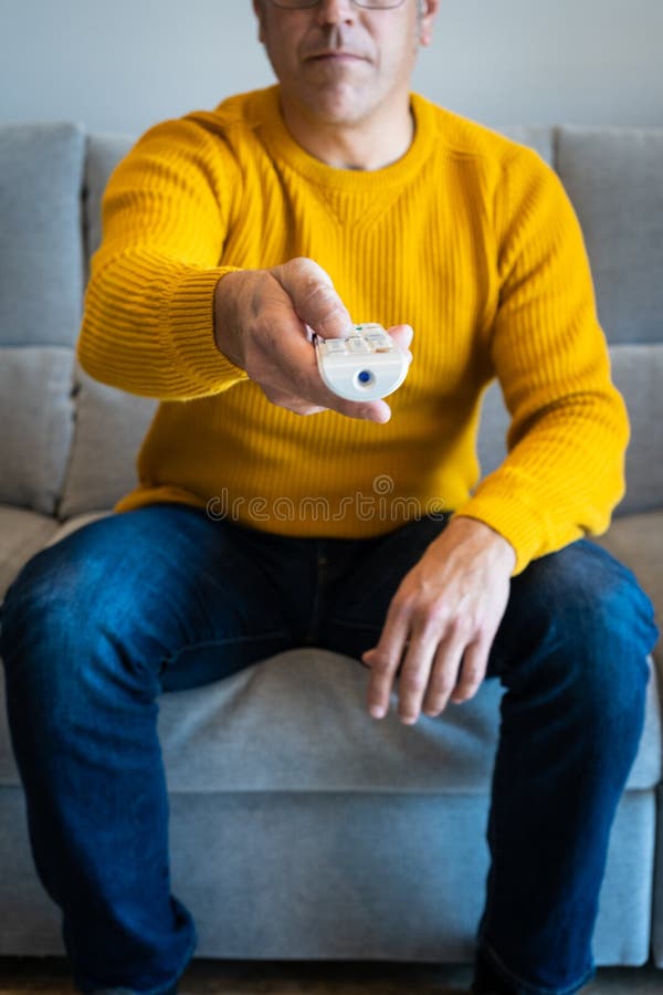 Man pointing with tv`s remote control towards camera from sofa stock photos