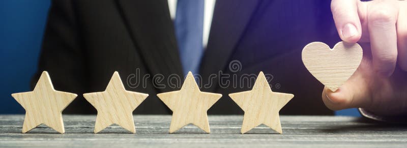 A man points to a heart instead of a fifth star. Loyalty and customer choice. The evaluation of visitors. Quality level, good service. Best customer rating. Feedback. Rating of hotels and restaurants