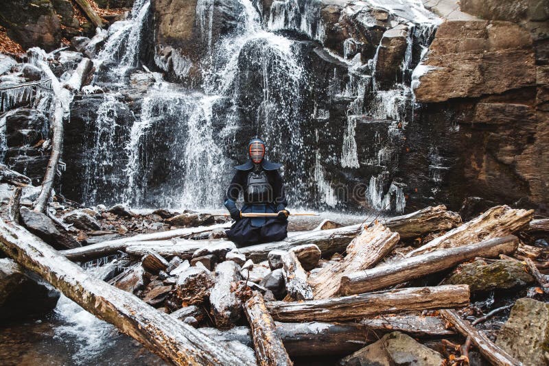 Man practicing kendo with bamboo sword on waterfall background. Place for text or advertising.