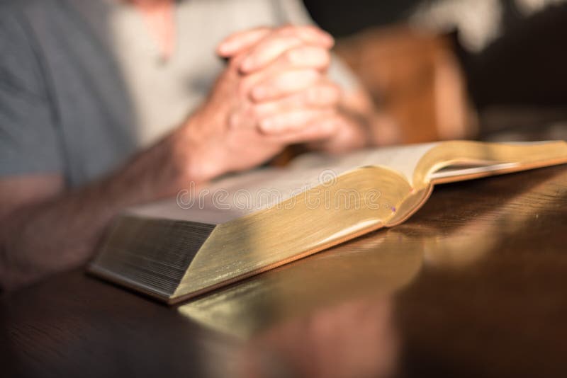 Man praying hands on a Bible stock photos Man praying hands on a Bible stock photos