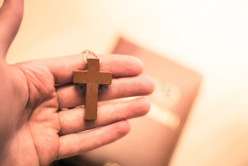 Man is praying: Rosary in the hands, holy bible in the background