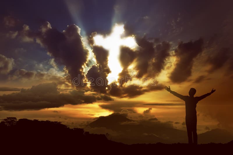 Man praying to god with ray of light shaping cross on the sky