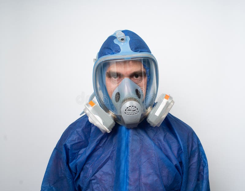 A Man in a Protective Blue Suit and Mask Holds a Sign Stock Image