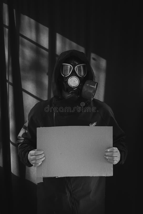 Man in a protective gas mask, holding a cardboard sign, a military. Respiratory protection from harmful substances, chemical. Weapons. Copy space. Vertical royalty free stock images Man in a protective gas mask, holding a cardboard sign, a military. Respiratory protection from harmful substances, chemical. Weapons. Copy space. Vertical royalty free stock images