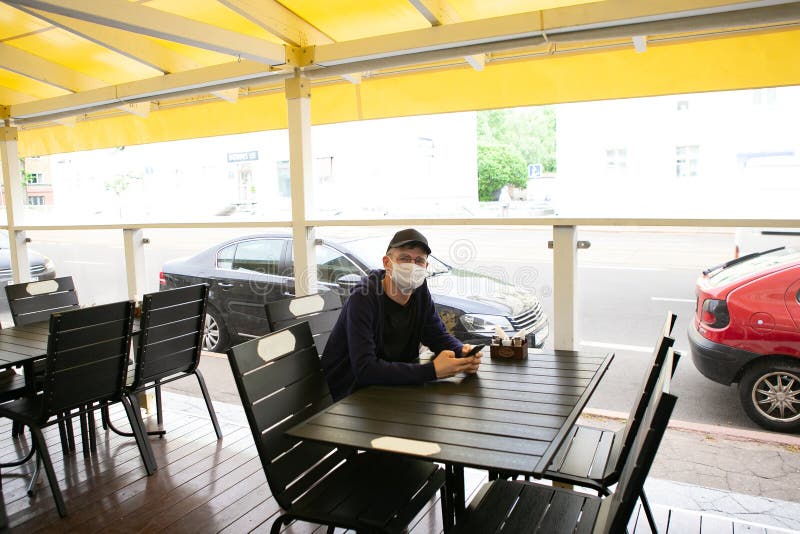 Man in protective mask is sitting in empty cafe