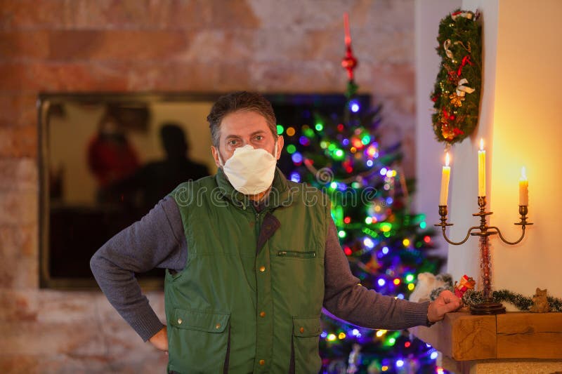 Man in protective mask stands in front of Christmas tree stock images