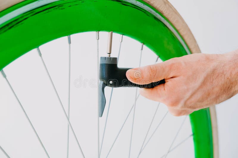 A Man Pumps Up a Green Bicycle Wheel with a Hand Pump Stock Image