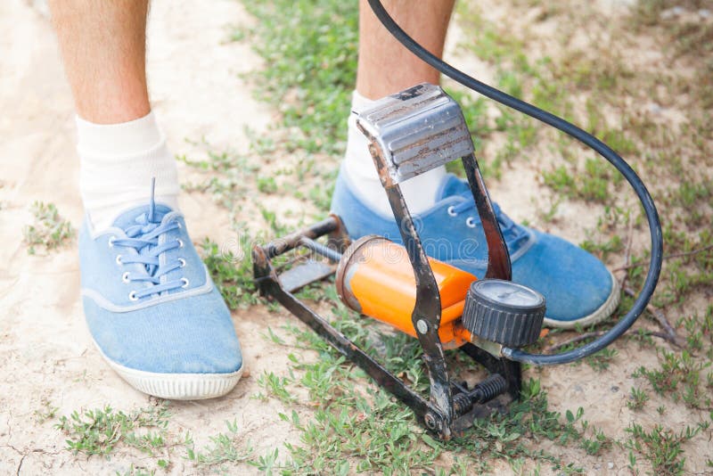 A Man Pumps Air into the Wheel of an Electric Scooter Using a Special