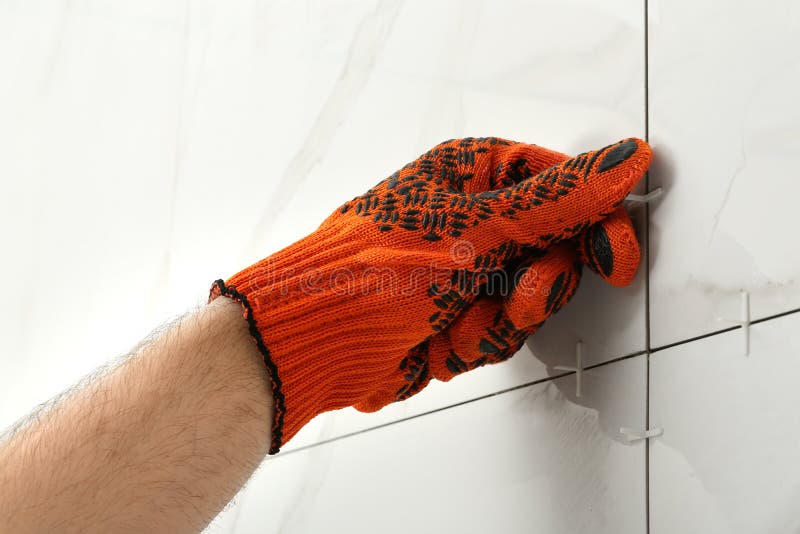 Man putting plastic cross into joint between ceramic tiles on wall. Building and renovation works stock image Man putting plastic cross into joint between ceramic tiles on wall. Building and renovation works stock image