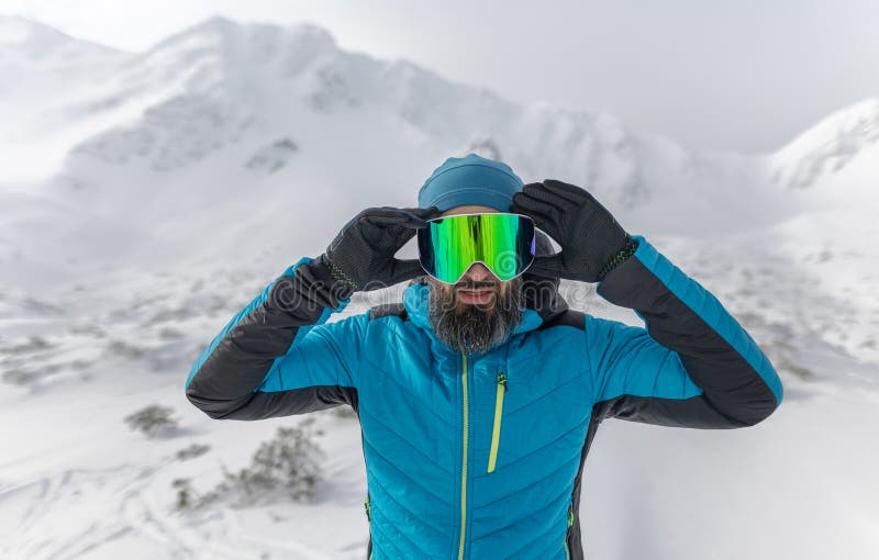 Muž si nasadil lyžiarske okuliare, pripravuje sa na zimné lyžovanie v zasnežených horách.
