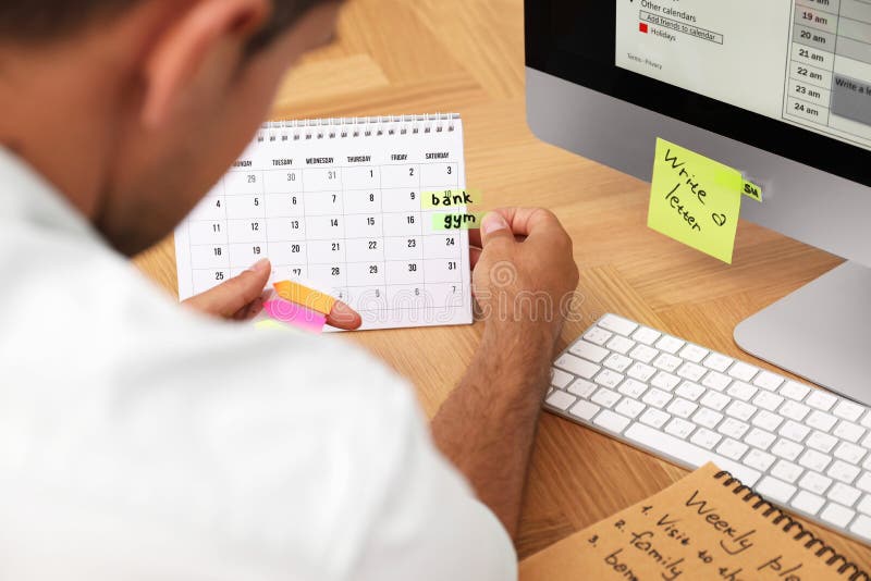 Man Putting Sticker on Calendar at Table in Office Stock Photo Image