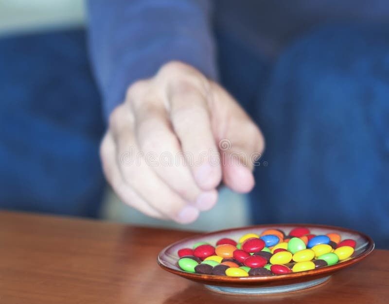 A Man Reaches for Colored Candies in a Dish Stock Photo Image of dish