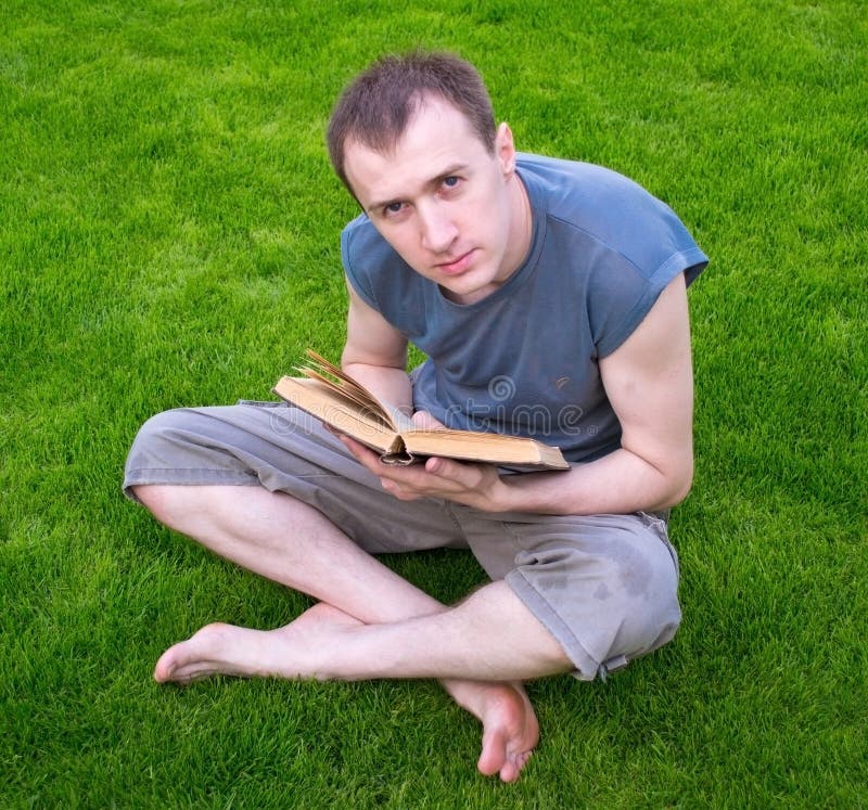 A man reading a book on the grass