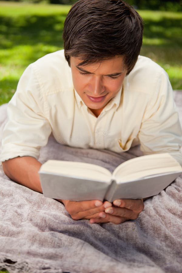 Man Reading Book while he Lies on a Blanket Stock Image Image of
