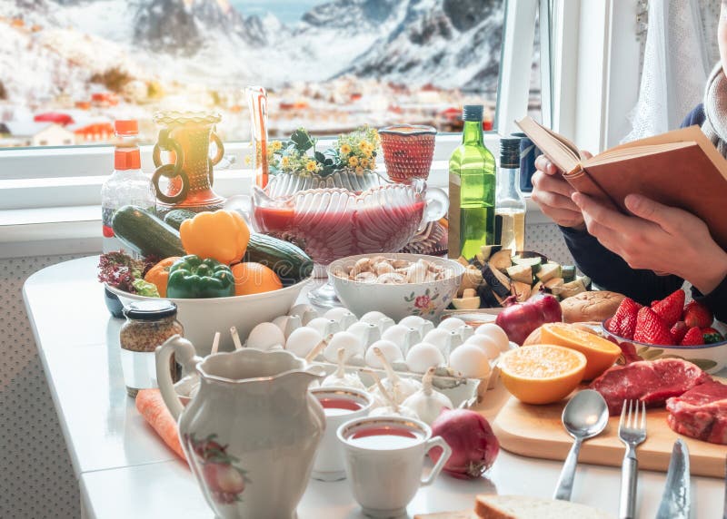 Man reading book with preparing food on dining table with snowing on village