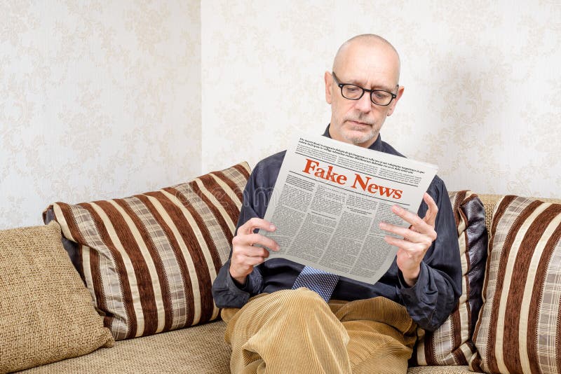 I was were reading a newspaper. Читает на диване планшет. Fake News stock photo.