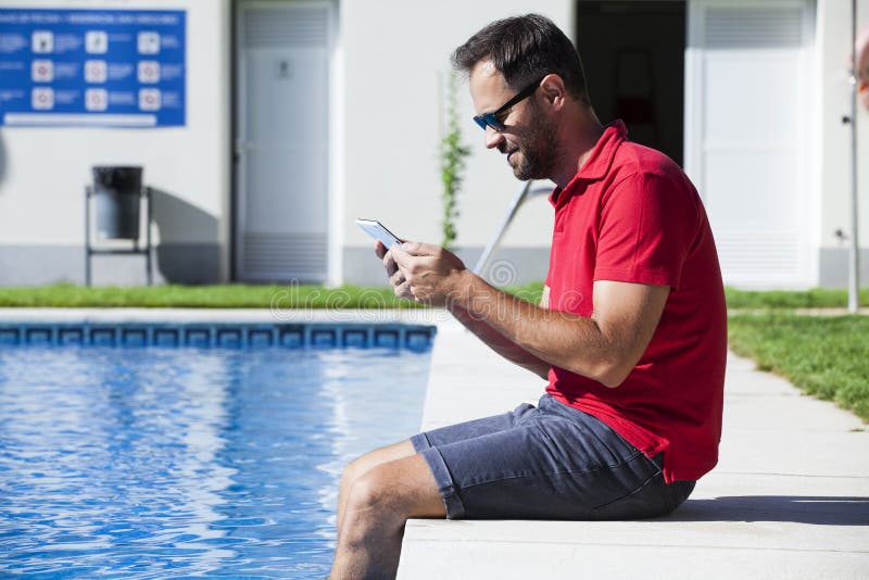 Man reading tablet sitting on the poolside. stock images Man reading tablet sitting on the poolside. stock images
