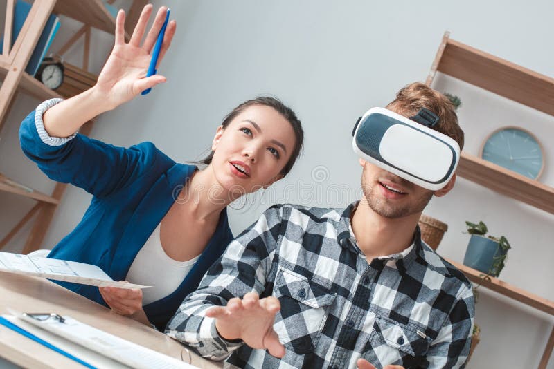 Young men at real estate agency sitting at table wearing virtual reality headset agent promoting client service dreamful. Young men at real estate agency sitting at table wearing virtual reality headset agent promoting client service dreamful