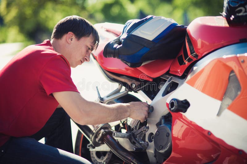 Man in a red T-shirt is repairing a motorcycle royalty free stock photos Man in a red T-shirt is repairing a motorcycle royalty free stock photos