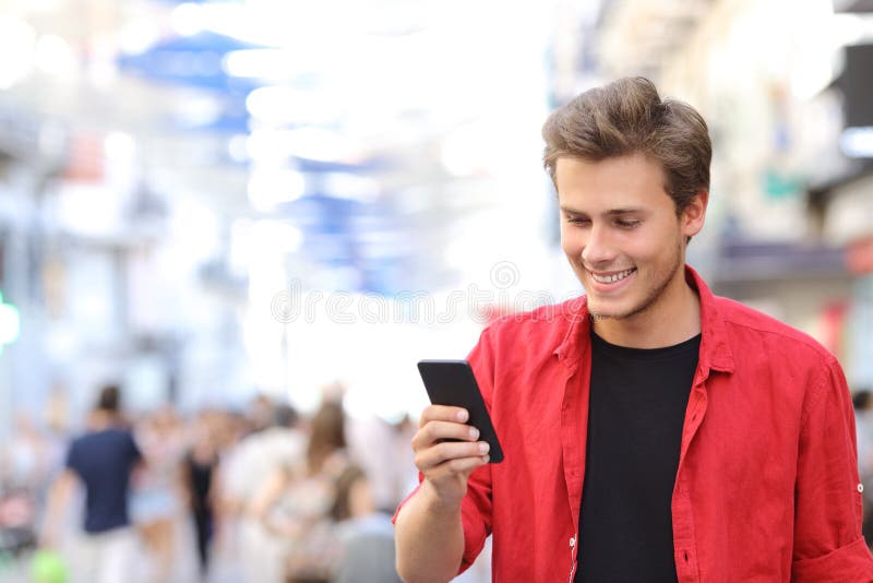 Happy man in red texting on a mobile phone in the street